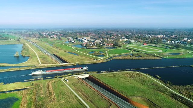 Big Cargo Boat Crossing an Aqueduct over a Road - Friesland, The Netherlands / Holland 4K Drone Footage