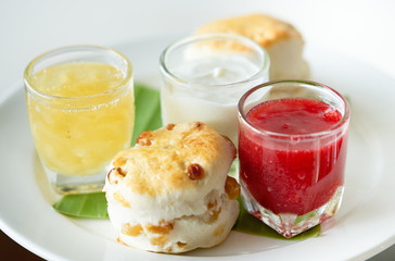 scone with pineapple jam and strawberry jam and cream in plate ,closed up