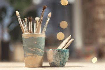 white cup with brushes and blank doll head, on a white background