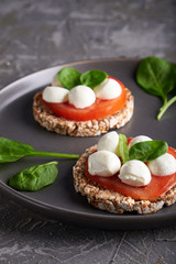 toasts with mozzarella, tomatoes and spinach in a gray plate