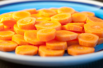 close-up of slices of raw carrot on a white and blue plate