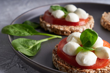 toasts with mozzarella, tomatoes and spinach in a gray plate
