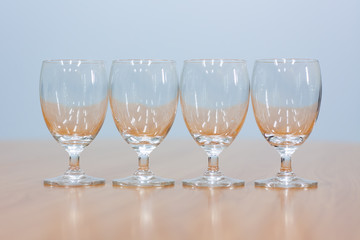Wine glasses lined up on a brown wooden table.