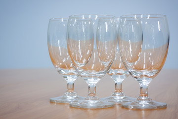Wine glasses lined up on a brown wooden table.