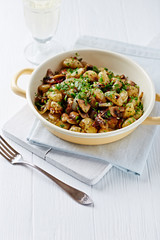 Gnocchi with onion and mushrooms. Bright wooden background. Copy space. 
