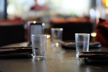 close up empty drinking glass on wooden dining table. Blur tableware and blur background