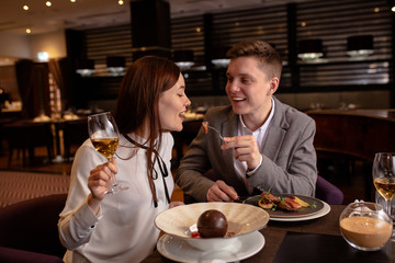 Try it! caucasian couple eat delicious food in luxury restaurant. young married couple treat each other with dessert. love, relationships, restaurant concept. indoors