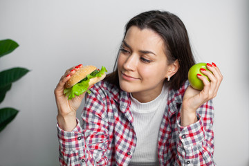 Fototapeta premium Cute woman makes a choice between healthy and harmful food
