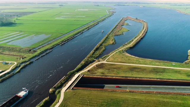 Long Shot of Big Ship Carrying Cargo Crossing an Aqueduct, Peaceful Dutch Flat Landscape, Upwards Shot - Friesland, The Netherlands / Holland 4K Drone Footage