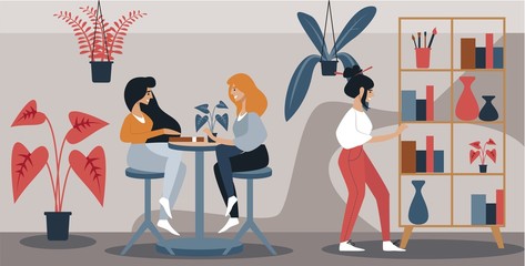 Meeting in Modern Art Cafe or Coworking Space. Two Smiling Girls Sitting Chatting at Table. Third Girl Considering Bookcase with Books and Vases. Potted Flowers Stand Indoors, Vector Illustration