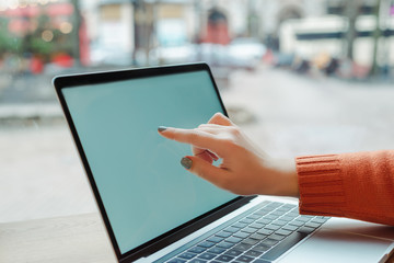 cropped view of girl pointing with finger at laptop screen on wooden table
