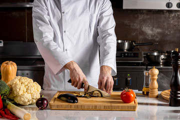 chef-cooker cut fresh vegetables on wooden board in kitchen, professional cook work in restaurant....