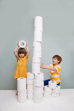 Two Kids Play Toilet Paper, Stand Tower In Home. Quarantine. Corona Virus. Stay Home Concept