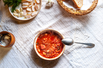 Ukrainian borsch - well served with cream, garlic, salo, on white rustic tablecloth, top view