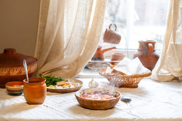Ukrainian borsch well served in vilage house in authentic ceramic tableware with cream, garlic,...