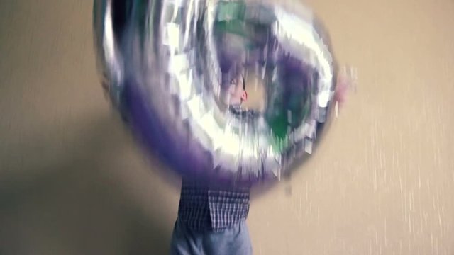 A joyful boy who is 6 years old of European appearance throws up an inflatable balloon in the form of the number 6.Children's birthday is 6 years old.