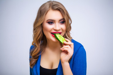 Cute woman eating green cucumber with lots of vitamins