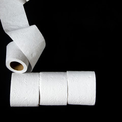 Rolls of white toilet paper lie on a black background