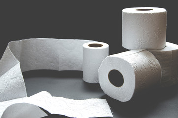 Rolls of white toilet paper lie on a black background