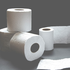 Rolls of white toilet paper lie on a black background