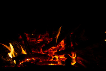 Red coals with fire on a black background. Burning coals and wood in the fire. Burning wood to keep warm and heat.