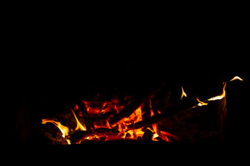 Red coals with fire on a black background. Burning coals and wood in the fire. Burning wood to keep...