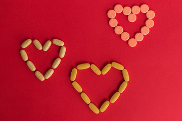 Healthy concept with Pharmaceutical medicine pills, tablets and capsules on red background. Medicine hearts love creative concepts. medical pattern, top view, flat lay. Copy space