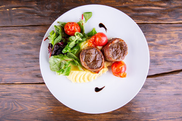 Meat beef medallions with lettuce leaves and vegetables