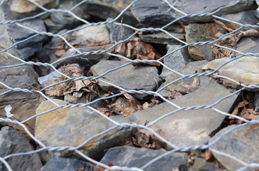 stone fence in a steel mesh. background of stones