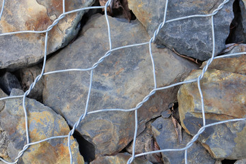 stone fence in a steel mesh. background of stones