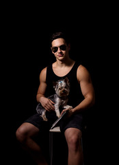 young sporty guy with a dog on a black background. studio photo