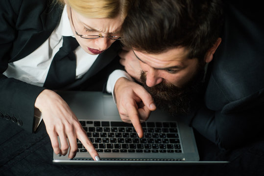 Business couple using laptop. Two partners working with laptop together. Little team of business people looking together at laptop.