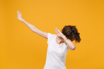 Young brunette woman in white t-shirt posing isolated on yellow orange wall background studio portrait. People sincere emotions lifestyle concept. Mock up copy space. Showing DAB dance gesture.