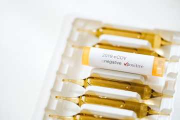  Coronavirus positive test sample and vaccine capsules on a white backgorund. Coronavirus / healthcare concept.