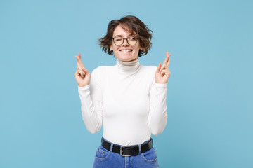 Pensive young woman girl in white clothes, eyeglasses isolated on pastel blue background. People...