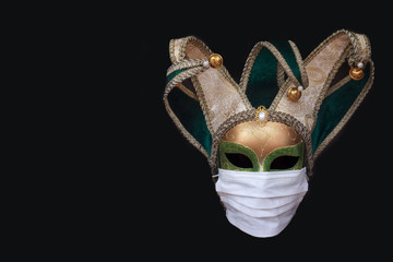 Classic venetian carnival mask in a medical protective mask isolated on a black background. The concept of the spread of coronavirus in Italy.