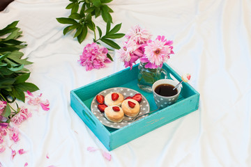 Breakfast in bed with cottage cheese pancakes, fresh strawberries, peonies and cup of coffee.