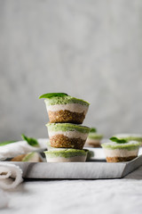 Stack of three healthy no bake bites in three colors white, green and orange lactose and gluten free on white linen