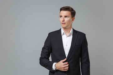 Shocked amazed young business man in classic black suit shirt posing isolated on grey wall background studio portrait. Achievement career wealth business concept. Mock up copy space. Looking aside.
