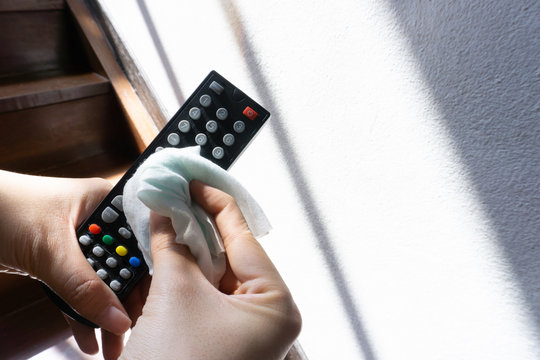 Woman hand clean remote control with alcohol to prevent outbreak covid19