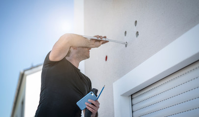 Handwerker misst mit einem Meterstab die Tiefe der Bohrlöcher