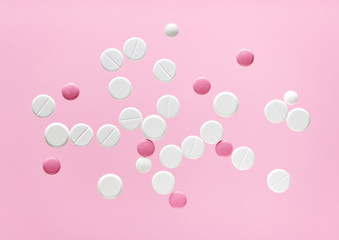 white and pink round medical pills on a color background