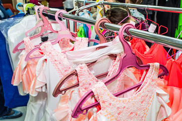 A row of stage costumes for upcoming performances by dance actors hangs on a floor hanger, toned.