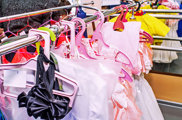 A row of stage costumes for upcoming performances by dance actors hangs on a floor hanger, toned.