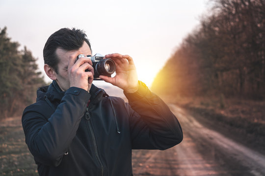 man takes pictures on an old mechanical camera on a background of nature