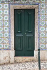 Lissabon, Portugal: Grüne Haustür umrahmt von typischen quadratischen Keramik Fliesen
