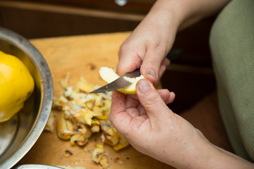 Quince fruit peeled with hands on a light background with space for an inscription . Woman peels quince .