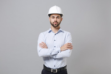 Confident young unshaven business man in light shirt protective construction helmet isolated on...