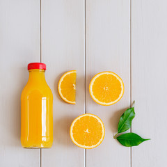 Orange juice in bottle and fresh citrus around. Healthy drink on a gray wooden background