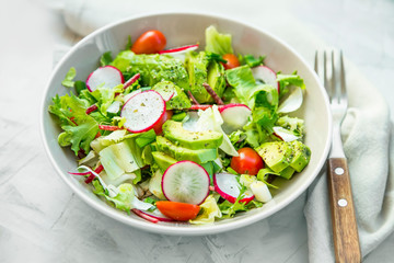 Fresh vegetable salad bowl closeup, healthy organic vegetables salad with radish, spinach, tomatoes, onion, avocado - 332194699
